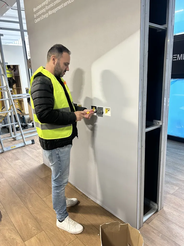 Installer in a high-visibility vest fitting KNX wall devices on a stand under construction