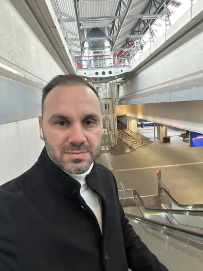 Portrait of a man in a dark coat on an escalator in a modern station hall